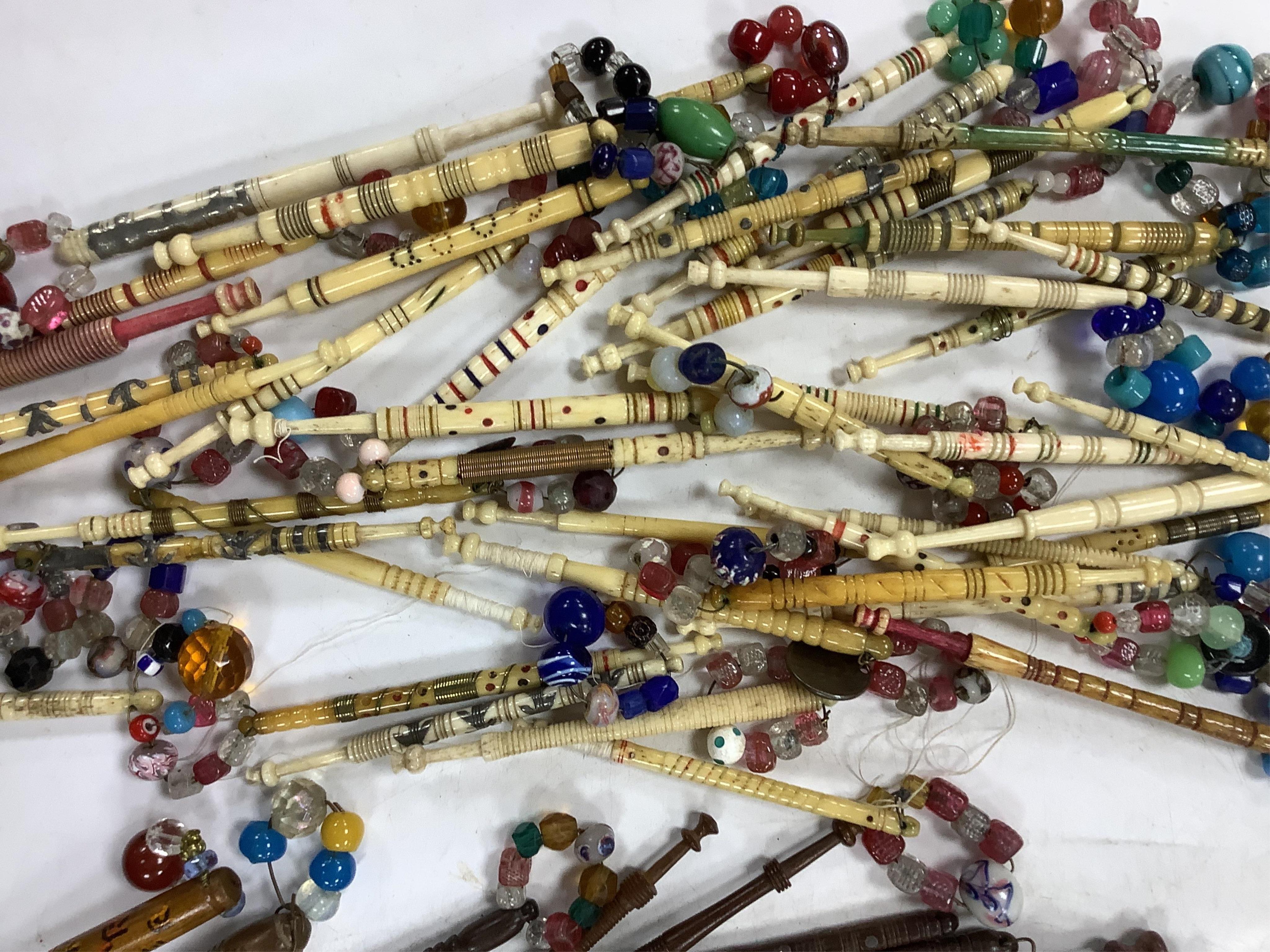 A collection of mostly 19th and 20th century ornate bone lace making bobbins, with coloured beaded ends, together with a similar smaller selection of wooden bobbins. Condition - good